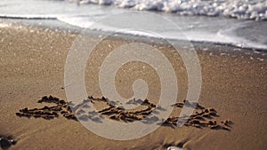 2022 figures on sandy beach Happy New Year 2022, number hand written in the golden sand on beautiful sunset golden light