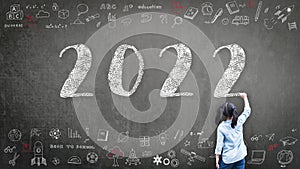 2022 Happy new year school class academic calendar with student kid\'s hand drawing greeting on teacher black chalkboard