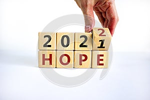 2022 hope new year symbol. Businessman turns a wooden cube and changes words `Hope 2021` to `Hope 2022`. Beautiful white