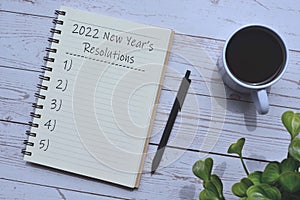 2022 New Year`s Resolutions list on notepad on wooden background