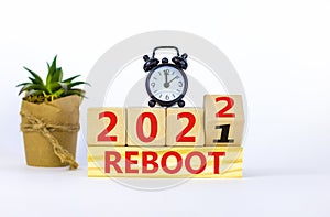 2022 reboot new year symbol. Alarm clock. Turned a wooden cube, changed words `Reboot 2021` to `Reboot 2022`. Beautiful white