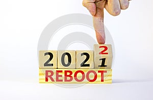 2022 reboot new year symbol. Businessman turns a wooden cube and changes words `Reboot 2021` to `Reboot 2022`. Beautiful white