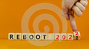 2022 reboot new year symbol. Businessman turns wooden cubes and changes words `Reboot 2021` to `Reboot 2022`. Beautiful orange