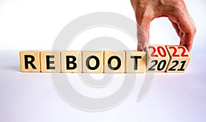 2022 reboot new year symbol. Businessman turns wooden cubes and changes words `Reboot 2021` to `Reboot 2022`. Beautiful white