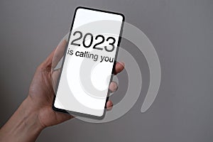 2023 Is Calling You concept with hand holding a smartphone.