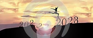 2023 Happy New Year concept, Young woman Jumping across the gap of the mountain from Old year 2022 to 2023 New Year