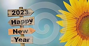 2023 happy new year written on a direction sign with petals of sun flower