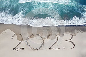 2023 numbers written on the sand of coastline