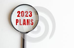 2023 PLANS text written on gray background. We read it through a magnifying glass.