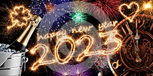 2023 sparkler number with golden clock champagne bottle in silver cooler and colorful fireworks display on dark black. happy new