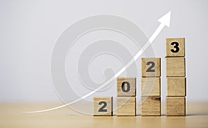 2023 year print screen on wooden cube block with increasing arrow for start new business year and growth concept