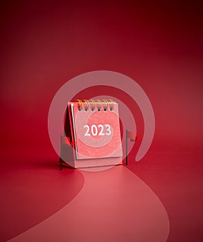 2023 year small red desk calendar standing between finish flags on road to success on red background.