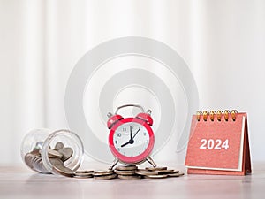 2024 desk calendar and Red alarm on stack of coins. The concept of saving money and manage time to success Financial, Investment