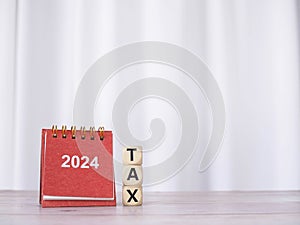 2024 desk calendar and Wooden blocks with the word TAX. The concept about prepare to pay tax in new year 2024