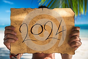 2024 Happy New Year from island. Tourist man with Santa Claus hat relaxing on tropical beach Punta Cana, Dominican Republic