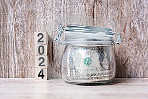 2024 Happy New Year with US dollar money glass American on wood table background. business, investment, retirement planning,