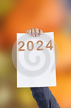 2024, Man holding cardboard with number 2024 on orange background. Happy New Year