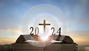 2024 new year and cross of jesus christ on open holy bible with sunrise background