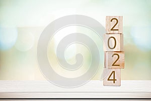 2024 new year greeting card, wooden cubes with 2024 on wood table over blur bokeh background with copy space for text, new year