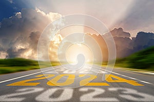 2024 New Year road trip travel and future vision concept. Number of the old year and New Year written on middle highway road in