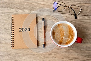 2024 notebook and coffee cup on wood table, Top view and copy space. Xmas, Happy New Year, Goals, Resolution, To do list, Strategy