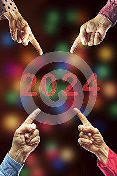 2024, People pointing to the number 2024 on background of faded lights. Happy New Year
