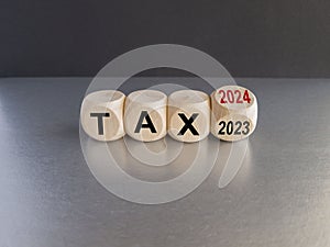 2024 tax new year symbol. Turned a wooden cube and changes words Tax 2023 to Tax 2024. Beautiful grey table black background, copy