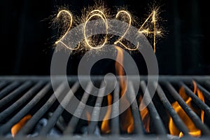 2024 written with sparklers on  empty, hot barbecue grill with orange flames, new year backdrop