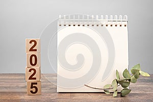 2025 mockup notepad. 2025 cubes wooden table background. New Year. plans for 2025, space for your text on notepad, mockup calendar