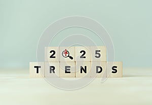 2025 trends, emerging markets concept. Wooden cube blocks with 2025, magnifying glass, TRENDS text.