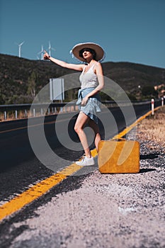 20s age One woman with a straw hat hitchhiking by the country roadside