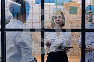 20s Asian company female manager brainstorming in the meeting room while having sticky notes on glass in office