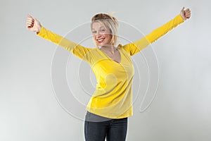 20s blond woman smiling with arms opened for joy