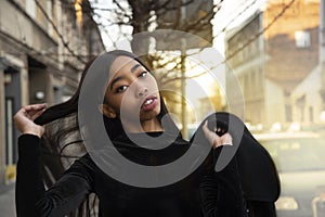 20s portrait of young African woman in black dress with hair with city street background