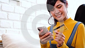 20s teenager Asian woman holding credit card and mobile phone in cozy white room
