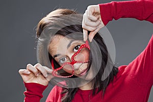 20s woman looking over her fun red glasses