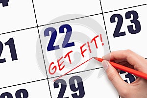 22nd day of the month. Hand writing text GET FIT and drawing a line on calendar date. Save the date.