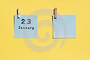 23 January. 23th day of the month, calendar date. Two blue sheets for writing on a yellow background. Top view, copy space. Winter