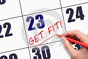 23rd day of the month. Hand writing text GET FIT and drawing a line on calendar date. Save the date.