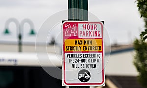 24 hour parking strictly enforced sign on a green post