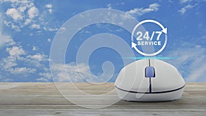 24 hours service flat icon with wireless computer mouse on wooden table over blue sky with white clouds, Business full time servic