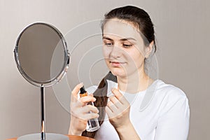 A 25-year-old woman holds a face and neck tonic and a cotton pad. Anti-wrinkle skin care, vitamins and acids for the