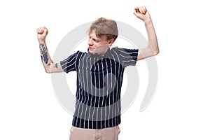 25s blond man dressed in a T-shirt with tattoos dancing on a white background