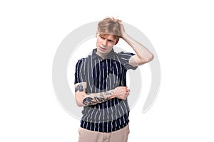 25s blond man dressed in a T-shirt with tattoos thinking on a white background