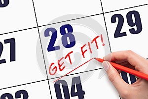 28th day of the month. Hand writing text GET FIT and drawing a line on calendar date. Save the date.