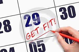 29th day of the month. Hand writing text GET FIT and drawing a line on calendar date. Save the date.