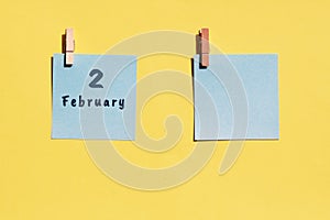 2st of February. 2st day of the month, calendar date. Two blue sheets for writing on a yellow background. Top view, copy space.