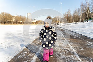 3-4 years old child walks along the wide embankment of a frozen pond in winter