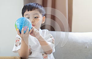 3.5 years asian little boy looking at Globe on his hands at home. Concept for research global warming