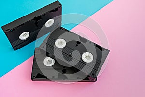 3 black VHS video tapes on a pink and blue background